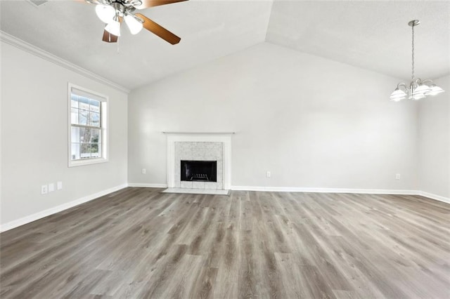 unfurnished living room featuring baseboards, a tile fireplace, lofted ceiling, wood finished floors, and ceiling fan with notable chandelier