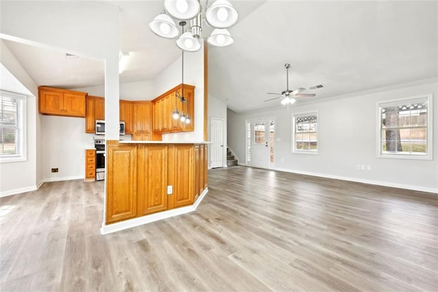 kitchen featuring brown cabinets, range, light countertops, open floor plan, and plenty of natural light