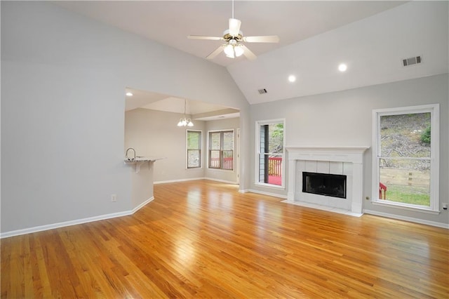 655 Golden Meadows Ln, Suwanee, GA 30024 - unfurnished living room featuring lofted ceiling, light wood-type flooring, a tile fireplace, a chandelier, and a ceiling fan