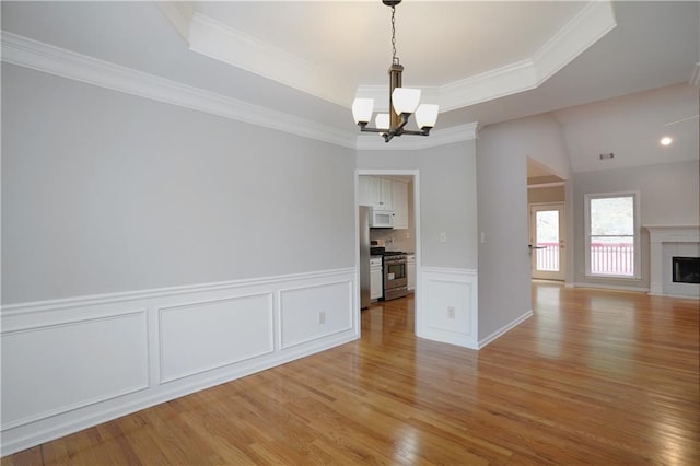 655 Golden Meadows Ln, Suwanee, GA 30024 - unfurnished dining area with a chandelier, a raised ceiling, light wood-style flooring, crown molding, and a decorative wall