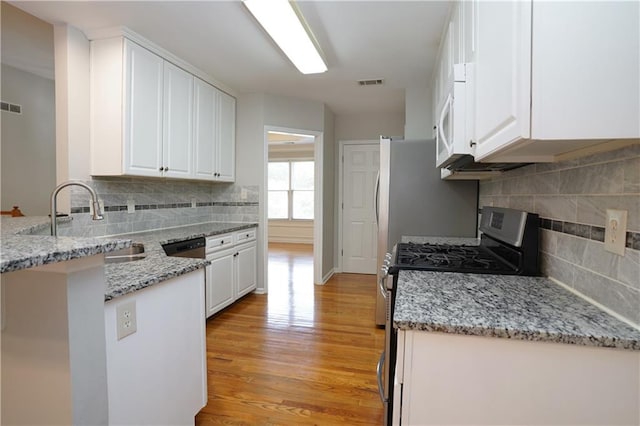 655 Golden Meadows Ln, Suwanee, GA 30024 - kitchen featuring stainless steel gas range oven, a peninsula, white cabinetry, and light wood finished floors