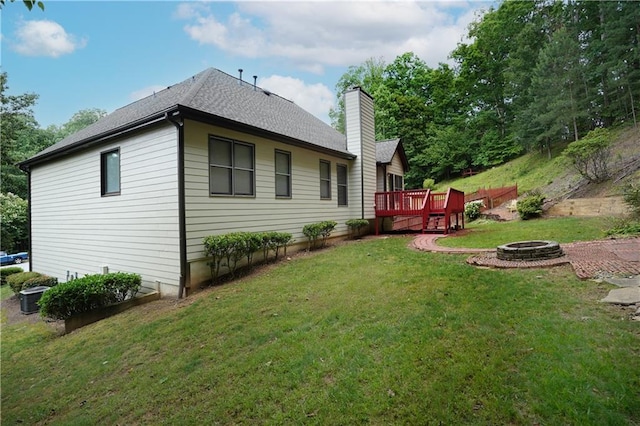 655 Golden Meadows Ln, Suwanee, GA 30024 - rear view of house with an outdoor fire pit, a chimney, a wooden deck, a lawn, and roof with shingles