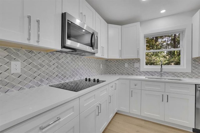 kitchen featuring backsplash, sink, light stone countertops, appliances with stainless steel finishes, and white cabinets