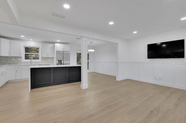 kitchen featuring built in refrigerator, light hardwood / wood-style floors, white cabinets, and tasteful backsplash