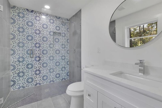 bathroom with toilet, a tile shower, tile patterned floors, and vanity