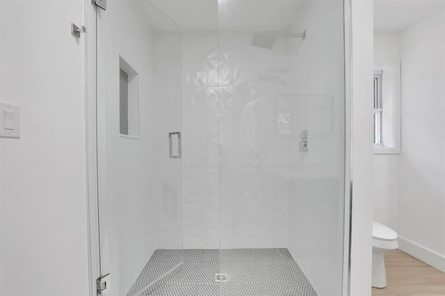 bathroom featuring toilet, hardwood / wood-style floors, and a shower with door