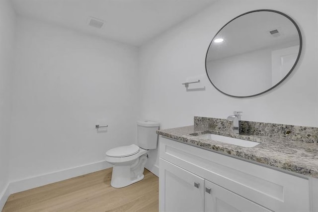 bathroom with toilet, vanity, and wood-type flooring