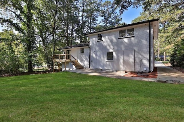 rear view of house featuring a wooden deck and a yard