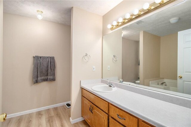 60 Cypress Dr, Covington, GA 30016 - bathroom with wood finished floors, vanity, a garden tub, and a textured ceiling