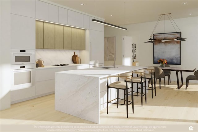 kitchen featuring decorative backsplash, modern cabinets, light wood-type flooring, double oven, and a sink