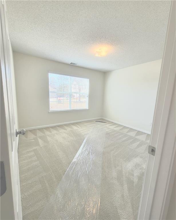 spare room with light carpet and a textured ceiling