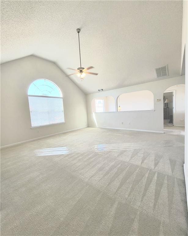 unfurnished room with ceiling fan, light colored carpet, vaulted ceiling, and a textured ceiling