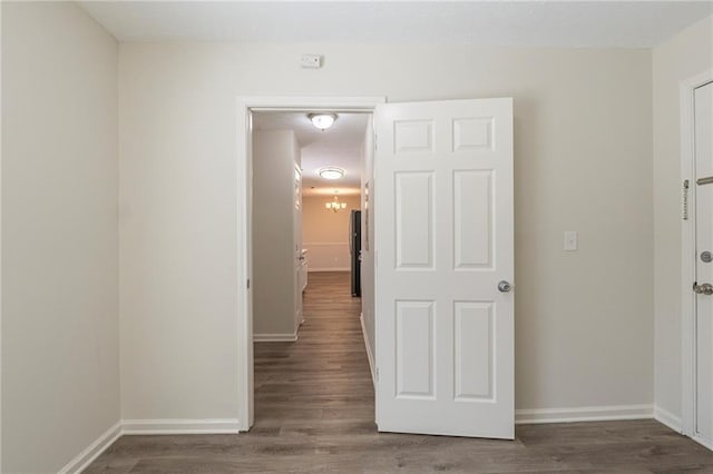 hallway with an inviting chandelier, wood finished floors, and baseboards