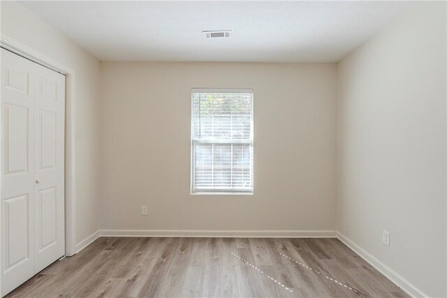 spare room with light wood-style floors, baseboards, and visible vents