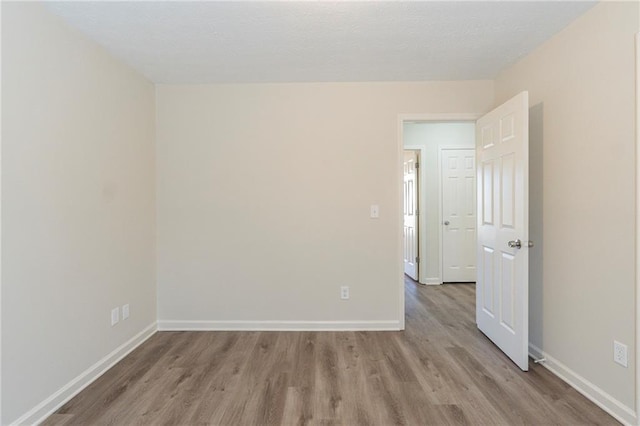 unfurnished room with baseboards and wood finished floors