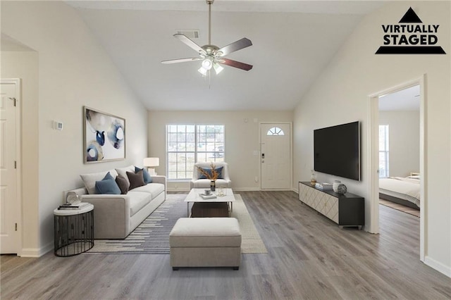 living area with ceiling fan, high vaulted ceiling, wood finished floors, and baseboards