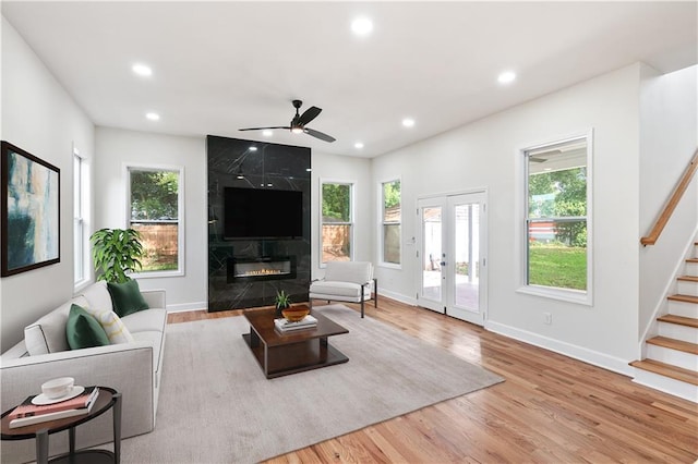 living room featuring plenty of natural light, ceiling fan, a fireplace, and light hardwood / wood-style flooring