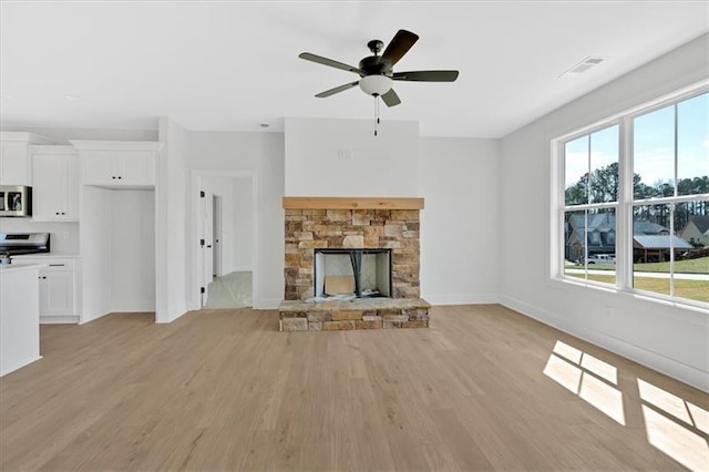 81 Bridgemill Dr, Douglasville, GA 30134 - unfurnished living room featuring a stone fireplace, light wood finished floors, and a ceiling fan