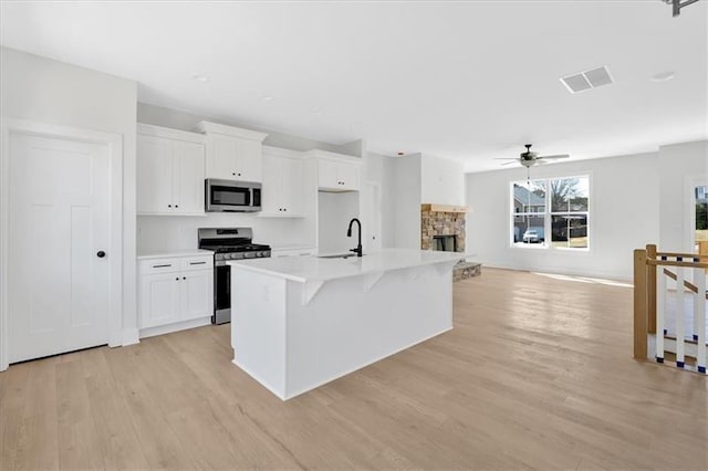 81 Bridgemill Dr, Douglasville, GA 30134 - kitchen with appliances with stainless steel finishes, a ceiling fan, white cabinetry, light wood finished floors, and light countertops