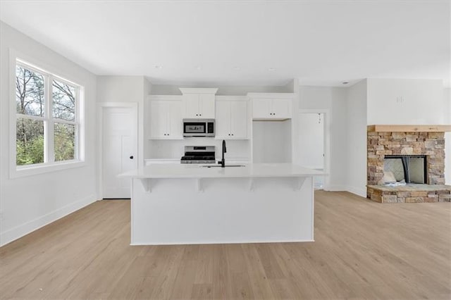 81 Bridgemill Dr, Douglasville, GA 30134 - kitchen with appliances with stainless steel finishes, a large island, white cabinetry, light countertops, and light wood finished floors