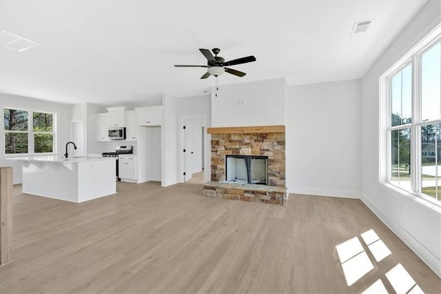 81 Bridgemill Dr, Douglasville, GA 30134 - unfurnished living room featuring light wood-type flooring, a ceiling fan, and a stone fireplace
