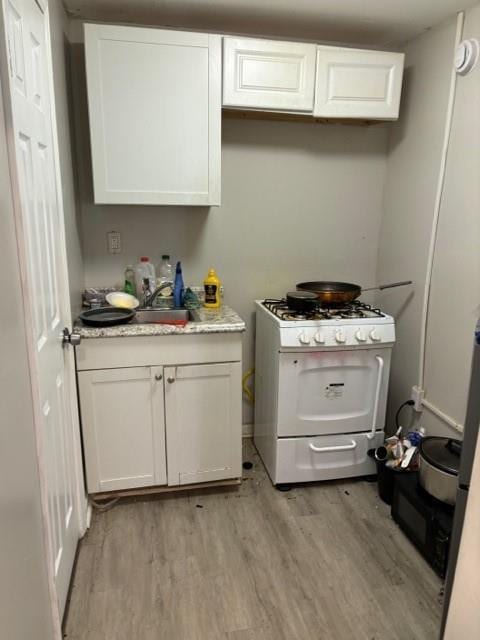 kitchen with gas range gas stove, light hardwood / wood-style floors, and white cabinetry