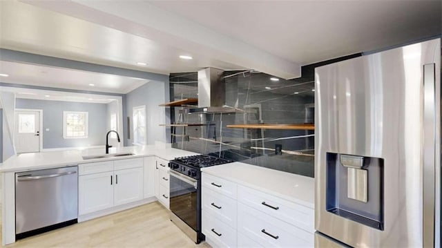 kitchen featuring white cabinets, appliances with stainless steel finishes, island range hood, light wood-type flooring, and sink