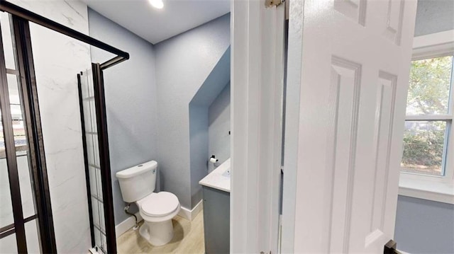 bathroom featuring toilet, a shower with shower door, and vanity