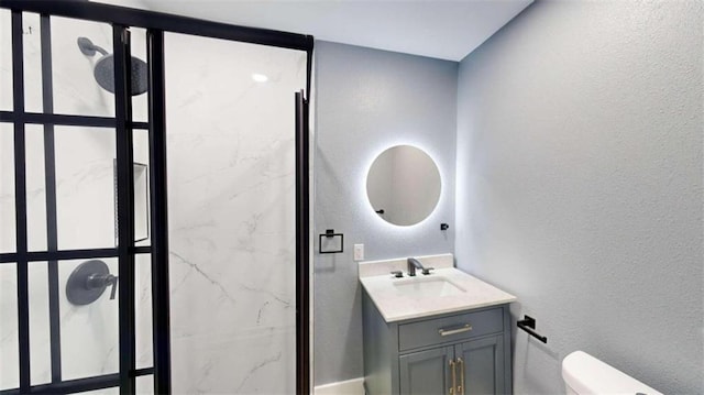 bathroom with vanity, a tile shower, and toilet