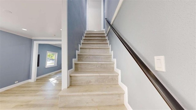 stairway with crown molding and wood-type flooring