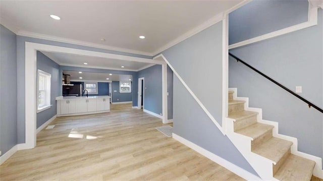 stairway with ornamental molding, sink, and wood-type flooring