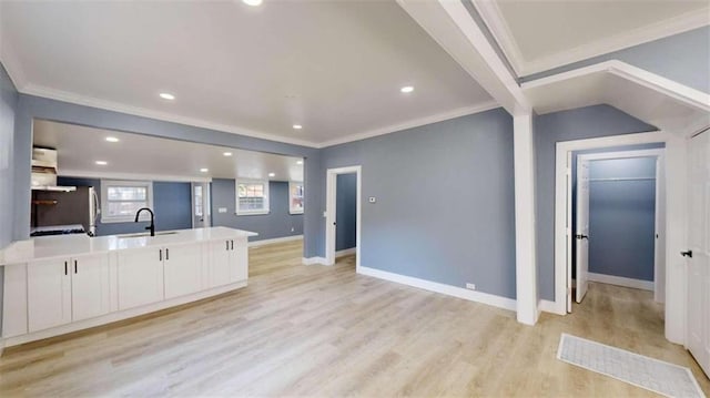 kitchen featuring white cabinets, a kitchen island with sink, light hardwood / wood-style flooring, crown molding, and sink