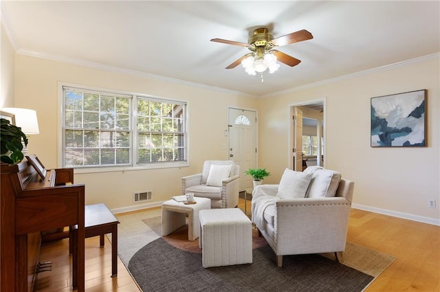 living room with ornamental molding, light hardwood / wood-style flooring, and ceiling fan