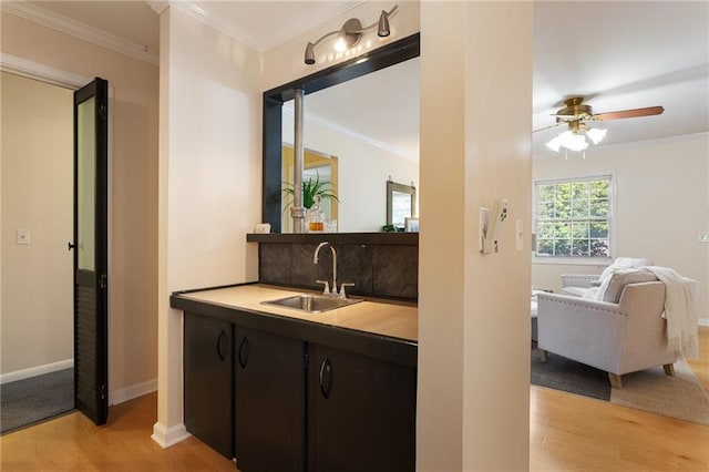 bar with crown molding, sink, light wood-type flooring, and ceiling fan