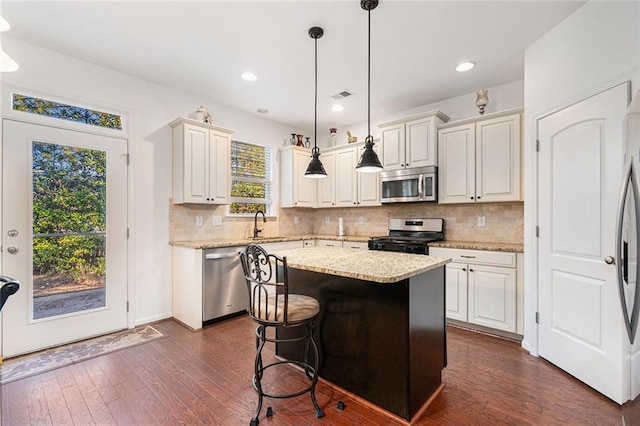 kitchen featuring stainless steel appliances, dark wood-style flooring, visible vents, backsplash, and decorative light fixtures