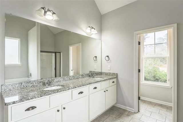 bathroom with lofted ceiling, a sink, baseboards, and double vanity