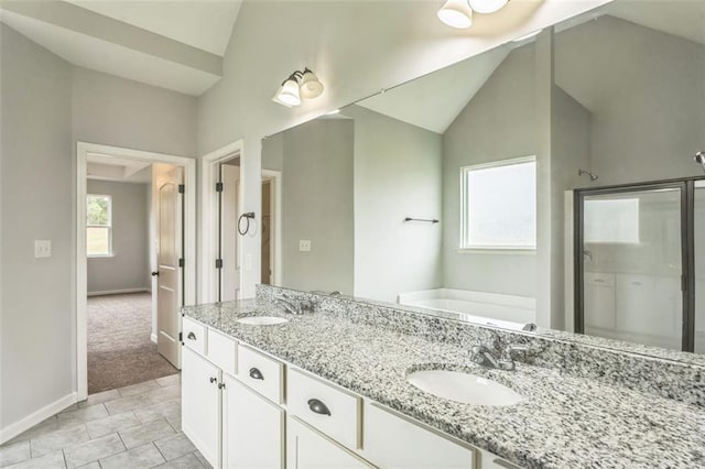 bathroom with a garden tub, a shower stall, vaulted ceiling, and a sink