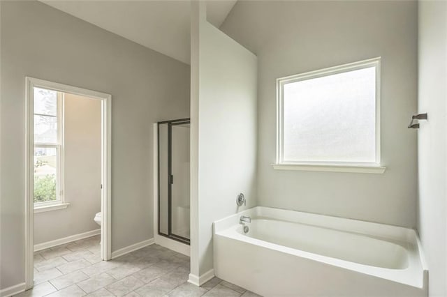 bathroom with a garden tub, a shower stall, and baseboards