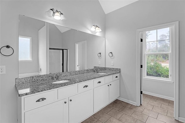 bathroom featuring a wealth of natural light, vaulted ceiling, a shower stall, and a sink