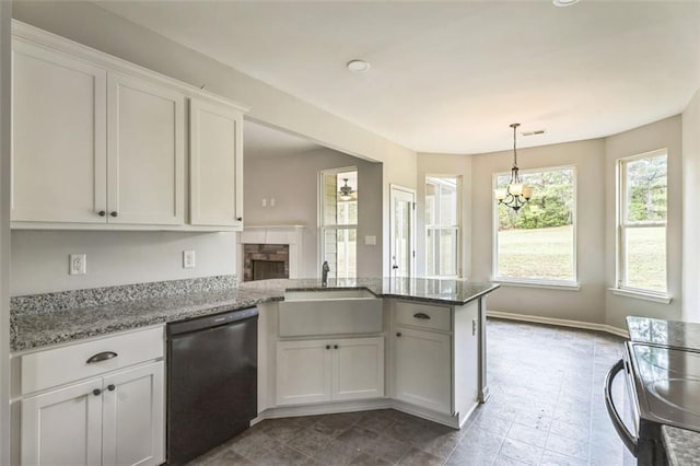 kitchen with light stone counters, a fireplace, white cabinets, a peninsula, and black appliances