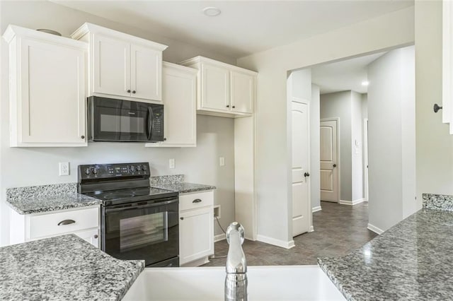 kitchen featuring black appliances, dark stone countertops, and white cabinets