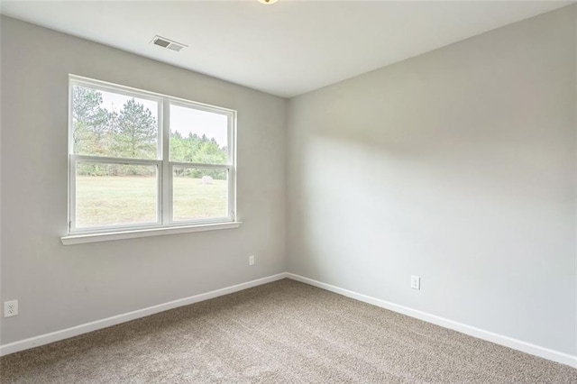 empty room with carpet floors, visible vents, and baseboards