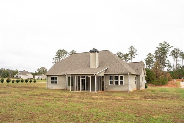 back of property with a sunroom, a yard, and a chimney