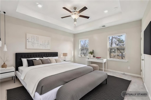 carpeted bedroom with a raised ceiling and ceiling fan