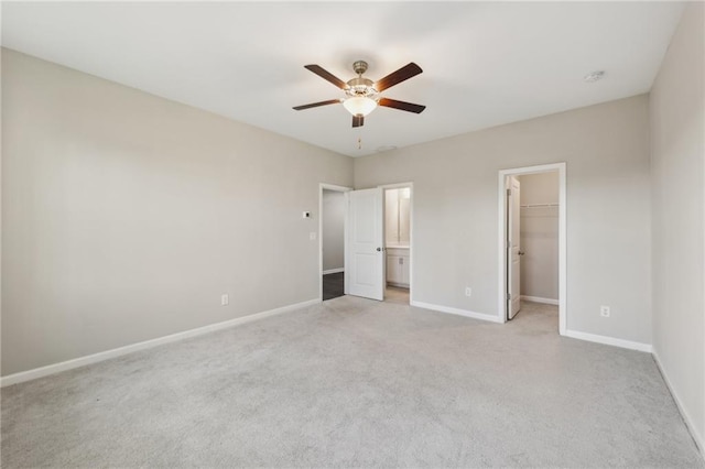 unfurnished bedroom with ceiling fan, a walk in closet, light colored carpet, and a closet