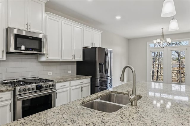 kitchen with sink, decorative light fixtures, white cabinets, and appliances with stainless steel finishes