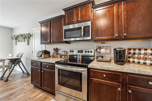 kitchen featuring stainless steel appliances, dark brown cabinetry, and light hardwood / wood-style flooring