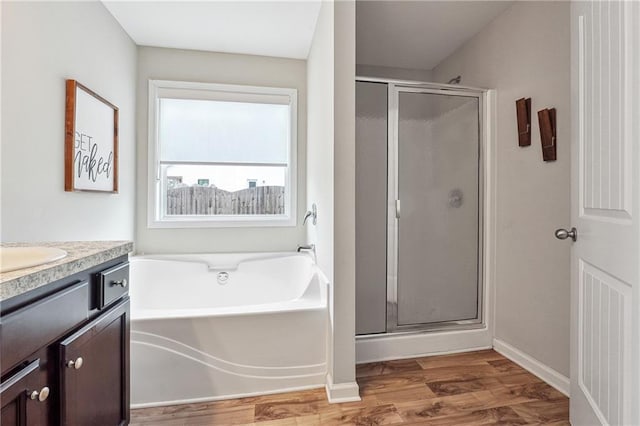 bathroom featuring vanity, hardwood / wood-style floors, and plus walk in shower