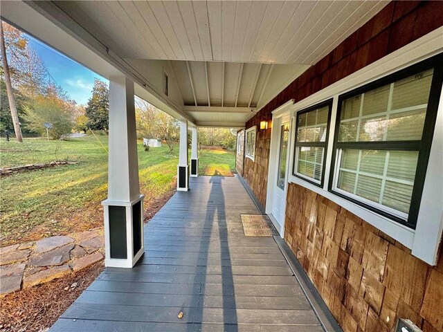 wooden terrace with a porch and a yard