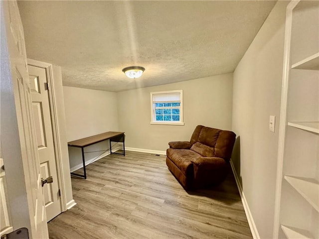 sitting room with light wood-type flooring and a textured ceiling